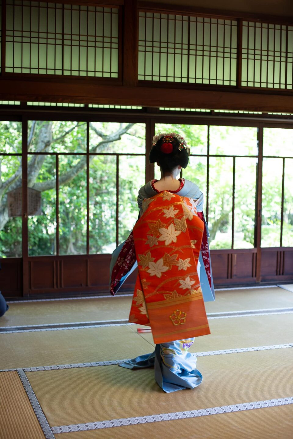 Long orange darari obi of a maiko seen from behind in a Kyoto tea house