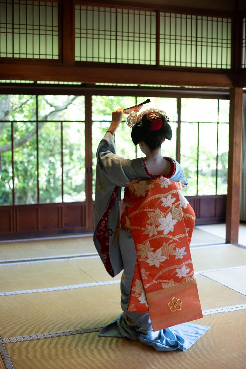 Maiko raising a folded fan during a traditional dance in Kyoto