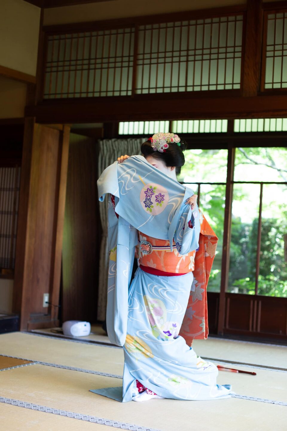 Maiko in a blue kimono performing a graceful dance pose in Kyoto