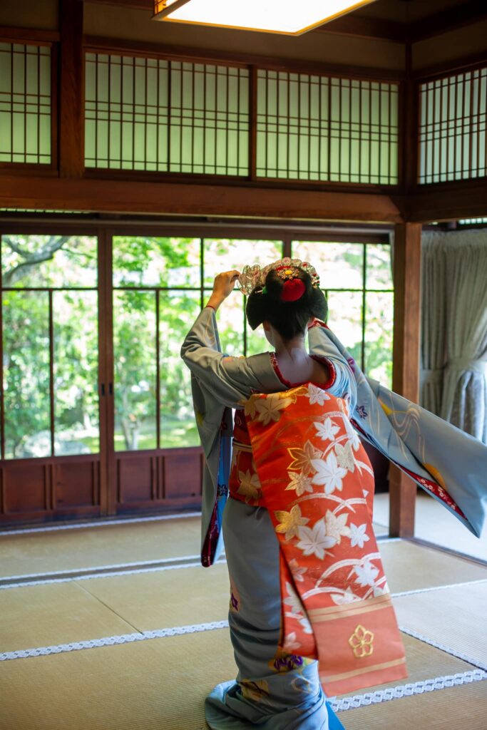 Maiko in an elegant dance pose in a Kyoto tatami room