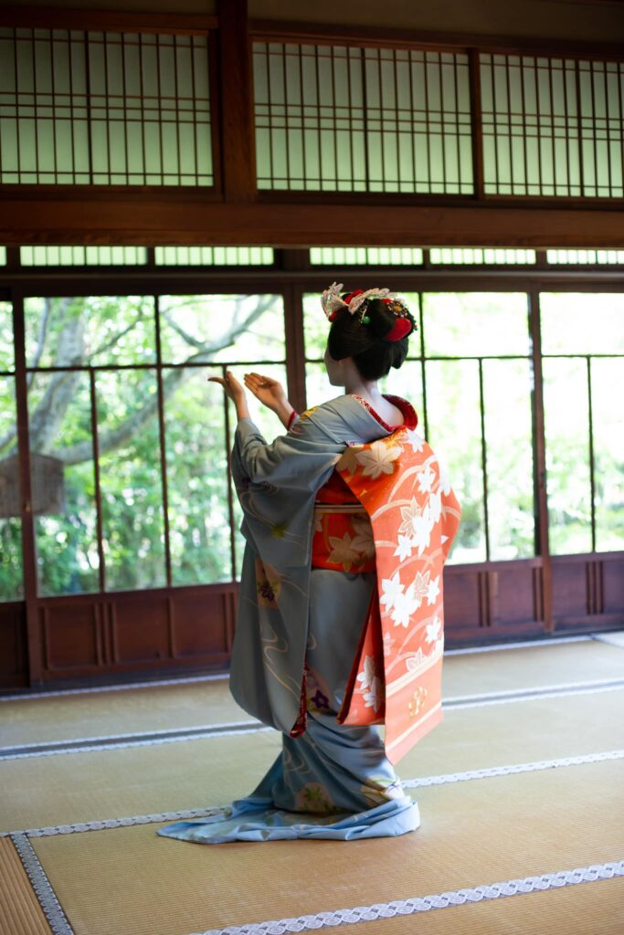 Maiko making an elegant hand gesture during a dance in Kyoto