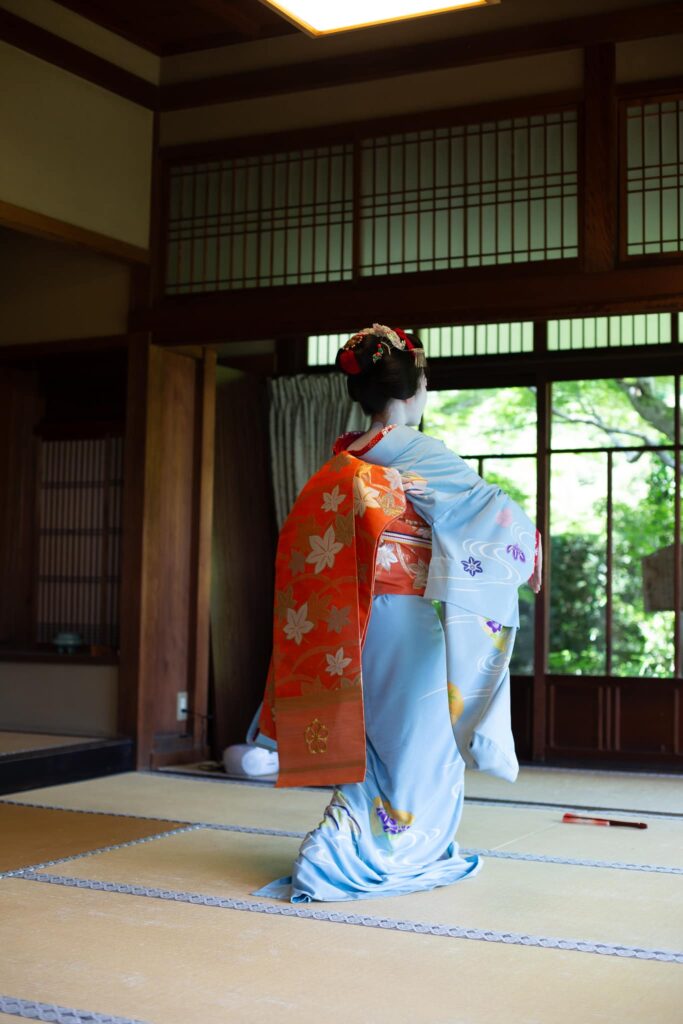 Maiko performing a traditional Kyoto dance in a tatami room with garden view